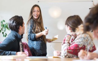 Eine Nachhilfelehrerin erklärt einer kleinen Gruppe am Tisch