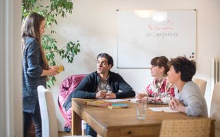 Vier Jugendliche arbeiten mit einer Lehrerin an einem großen Tisch im Lernstudio